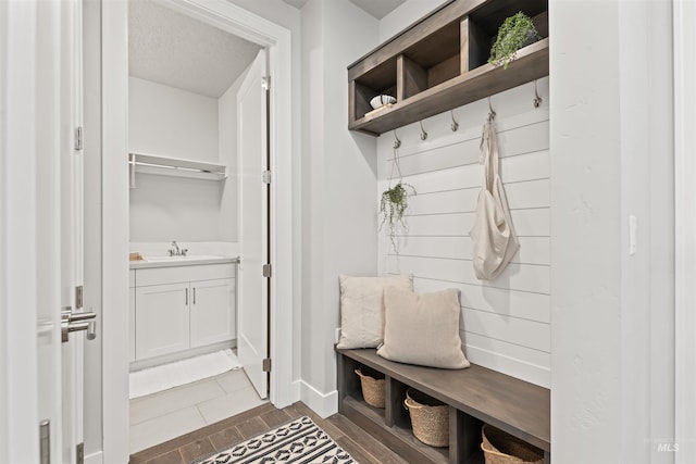 mudroom featuring dark wood finished floors, a sink, a textured ceiling, and baseboards