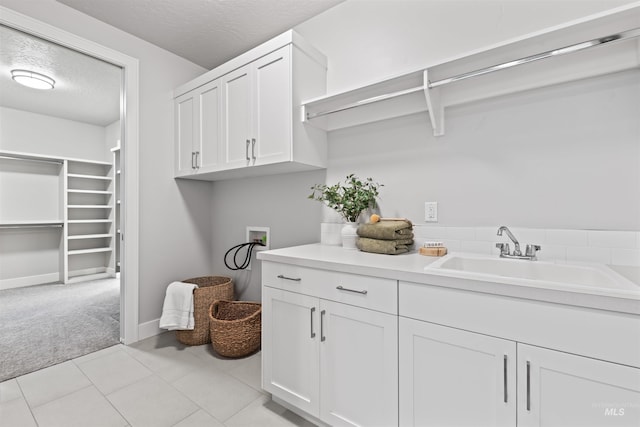 washroom with washer hookup, light colored carpet, cabinet space, a sink, and a textured ceiling