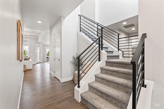 stairs featuring recessed lighting, visible vents, a textured ceiling, wood finished floors, and baseboards