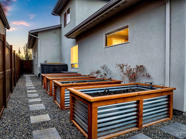 view of property exterior featuring fence, a garden, and stucco siding