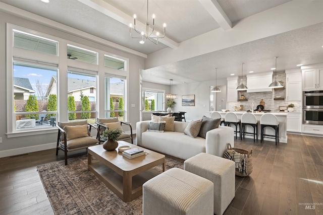 living area with a notable chandelier, dark wood-style flooring, visible vents, baseboards, and beamed ceiling