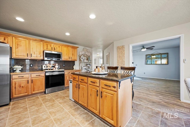 kitchen with a kitchen island, backsplash, recessed lighting, stainless steel appliances, and light tile patterned floors