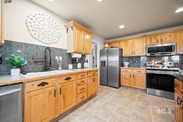 kitchen featuring light tile patterned floors, a sink, stainless steel appliances, light countertops, and backsplash