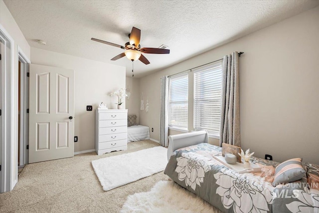 carpeted bedroom featuring baseboards, a textured ceiling, and ceiling fan