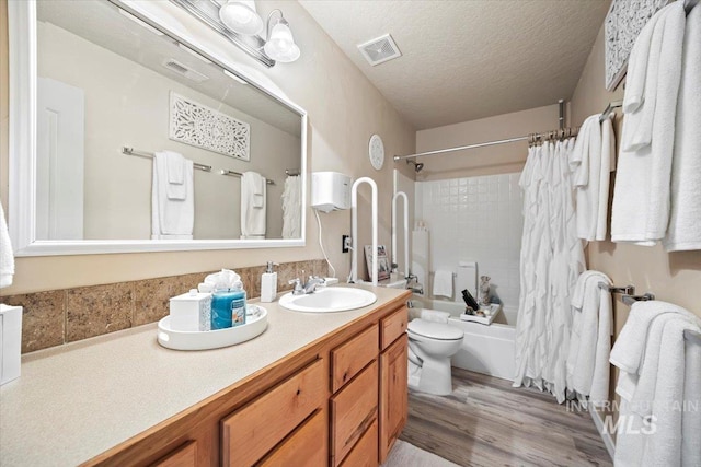 bathroom featuring vanity, visible vents, a textured ceiling, toilet, and shower / tub combo with curtain