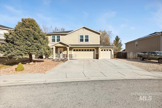 traditional-style home featuring an attached garage, fence, driveway, and stucco siding