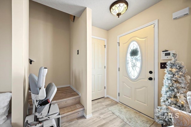 entrance foyer featuring light wood-type flooring, baseboards, and a textured ceiling