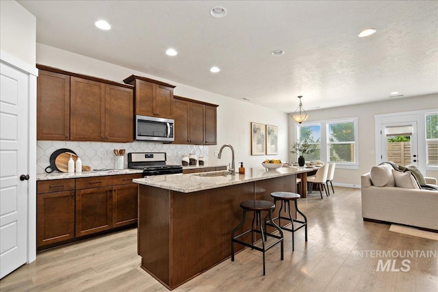 321 N Bay Haven Ave, Kuna, ID 83634 - kitchen featuring stainless steel appliances, a sink, backsplash, light wood-style flooring, and a kitchen breakfast bar