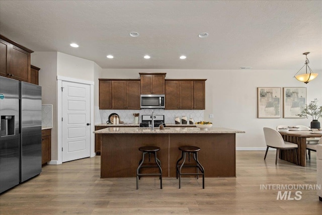 321 N Bay Haven Ave, Kuna, ID 83634 - kitchen featuring appliances with stainless steel finishes, decorative backsplash, baseboards, light wood-style floors, and recessed lighting