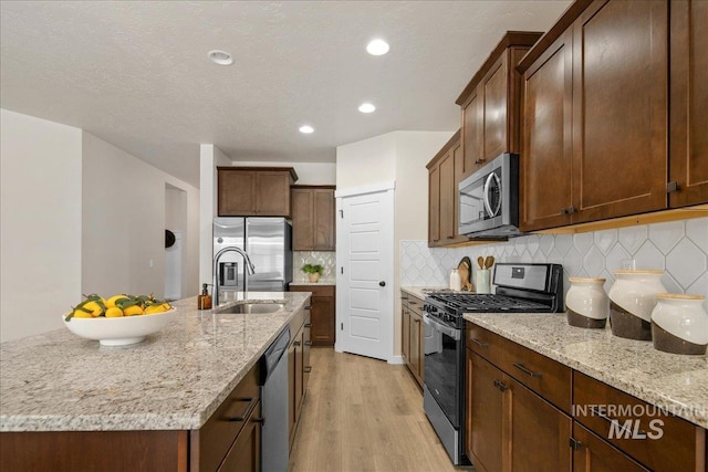 321 N Bay Haven Ave, Kuna, ID 83634 - kitchen featuring stainless steel appliances, a sink, light wood-style floors, light stone countertops, and backsplash