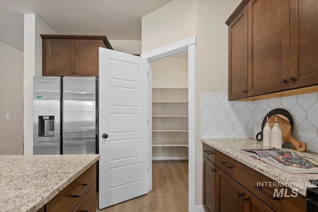 321 N Bay Haven Ave, Kuna, ID 83634 - kitchen with stainless steel fridge, light wood-type flooring, backsplash, and light stone counters