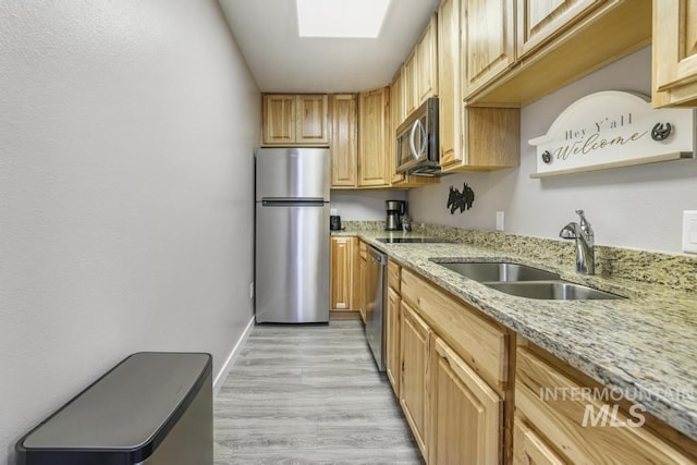 111 Main, Hagerman, ID 83332 - kitchen featuring stainless steel appliances, a sink, a skylight, light stone counters, and baseboards