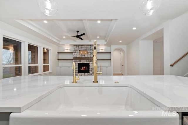 interior details featuring a fireplace, ceiling fan, light stone countertops, recessed lighting, and a sink