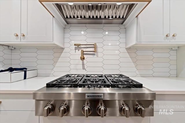 kitchen featuring stainless steel gas cooktop, custom exhaust hood, light countertops, and white cabinets