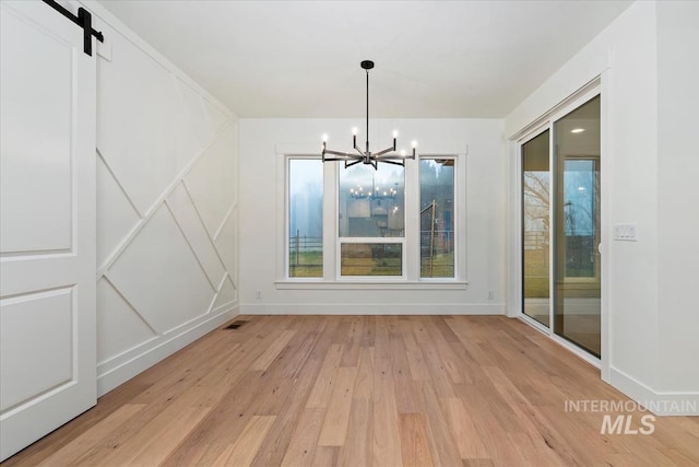 unfurnished dining area with baseboards, visible vents, light wood-style floors, and a notable chandelier