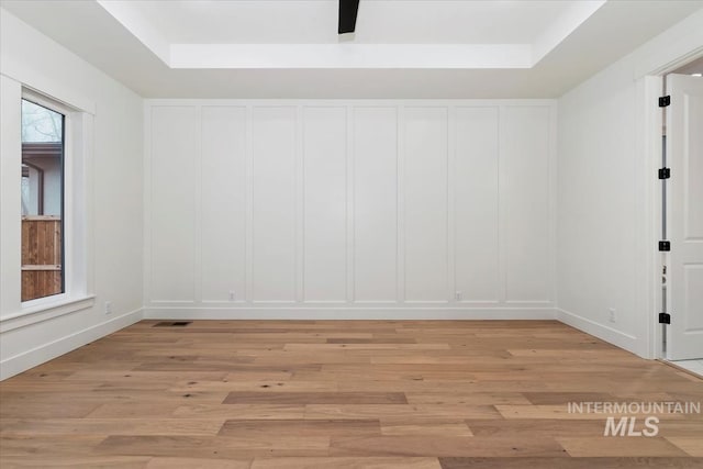 spare room with a decorative wall, light wood finished floors, and visible vents