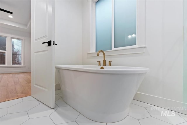 full bathroom featuring a freestanding tub, tile patterned floors, baseboards, and recessed lighting