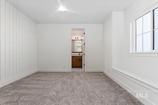 carpeted empty room featuring baseboards and ceiling fan