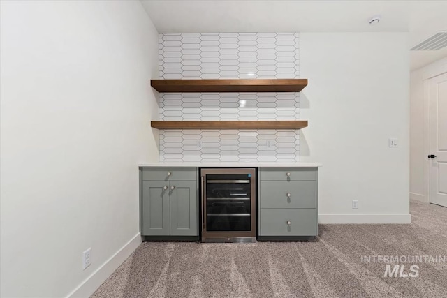 bar featuring visible vents, carpet, baseboards, and beverage cooler