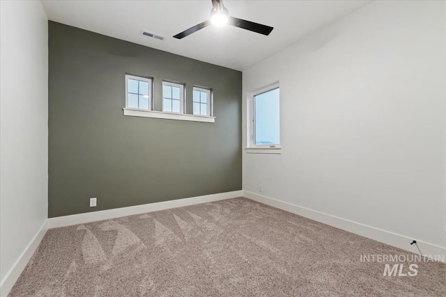 carpeted empty room featuring baseboards, ceiling fan, and visible vents