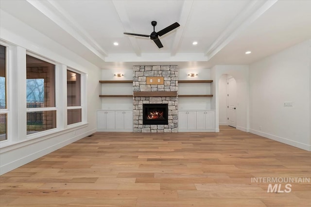 unfurnished living room featuring baseboards, beamed ceiling, light wood-type flooring, and a ceiling fan