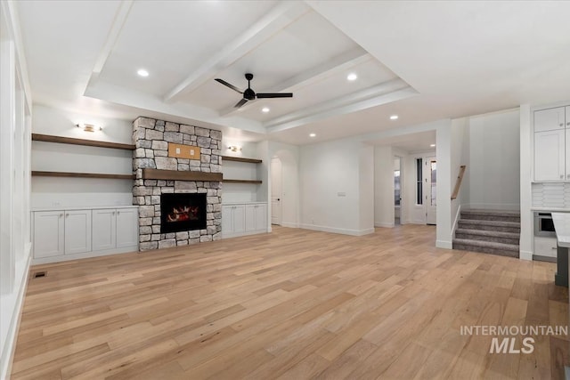 unfurnished living room featuring stairs, recessed lighting, light wood finished floors, ceiling fan, and a stone fireplace