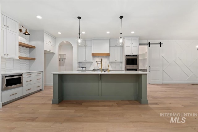 kitchen featuring light countertops, open shelves, double oven, light wood-style flooring, and custom exhaust hood