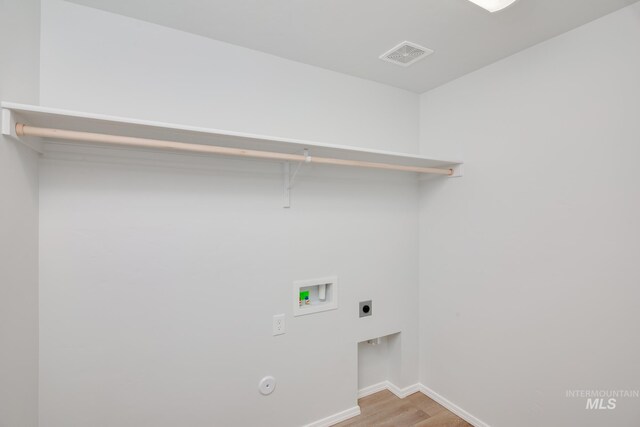 laundry area featuring electric dryer hookup, hookup for a washing machine, and light hardwood / wood-style flooring