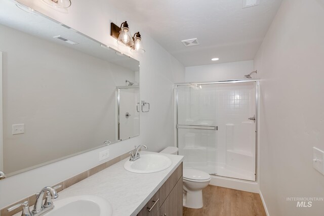 bathroom with hardwood / wood-style floors, vanity, toilet, and a shower with shower door