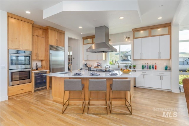 2391 S Trapper Pl, Boise, ID 83716 - kitchen featuring island exhaust hood, a sink, wine cooler, stainless steel appliances, and light wood-style flooring