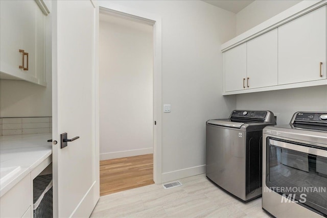 2391 S Trapper Pl, Boise, ID 83716 - laundry area featuring cabinet space, washing machine and clothes dryer, light wood-style flooring, baseboards, and visible vents