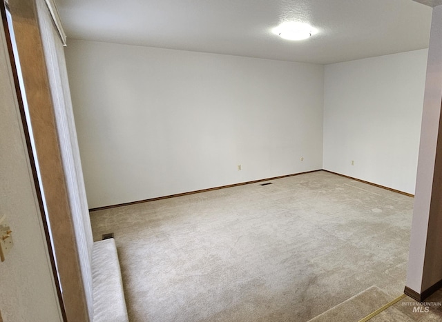 empty room with light colored carpet and a textured ceiling