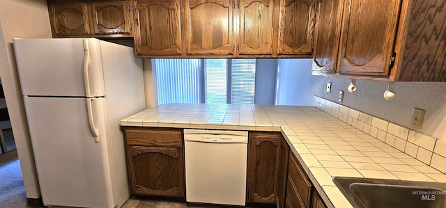 kitchen with tile countertops, white appliances, and kitchen peninsula