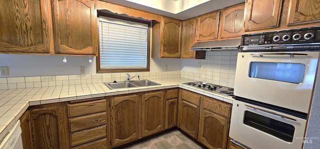 kitchen featuring sink, white double oven, range hood, gas stovetop, and tile countertops