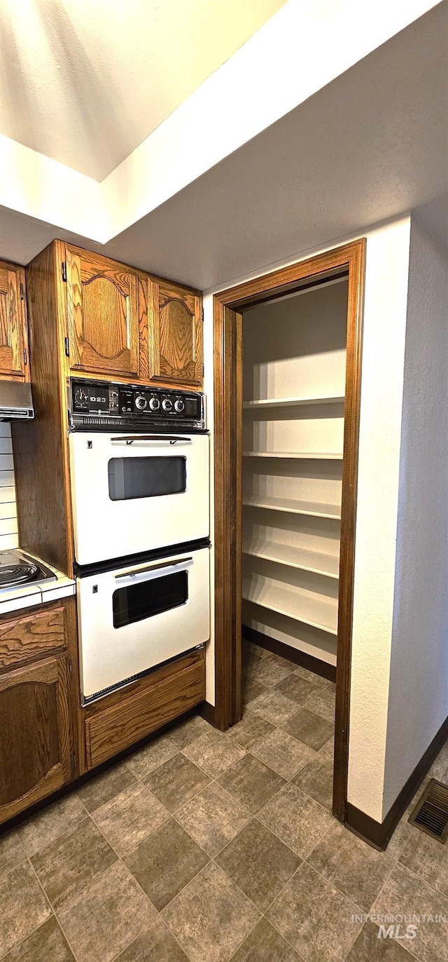 kitchen with cooktop, extractor fan, and white double oven