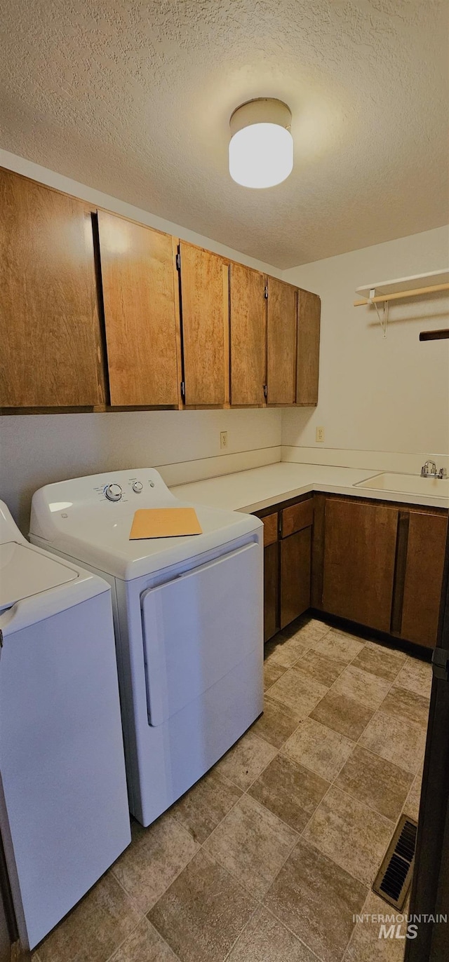 laundry area with independent washer and dryer, sink, cabinets, and a textured ceiling