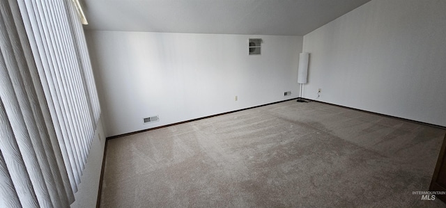 spare room featuring light carpet and vaulted ceiling