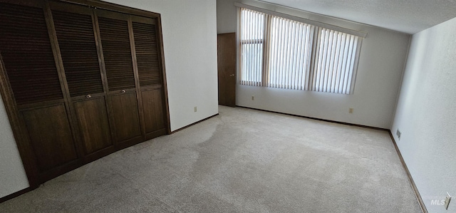 unfurnished bedroom featuring light colored carpet, a closet, and a textured ceiling
