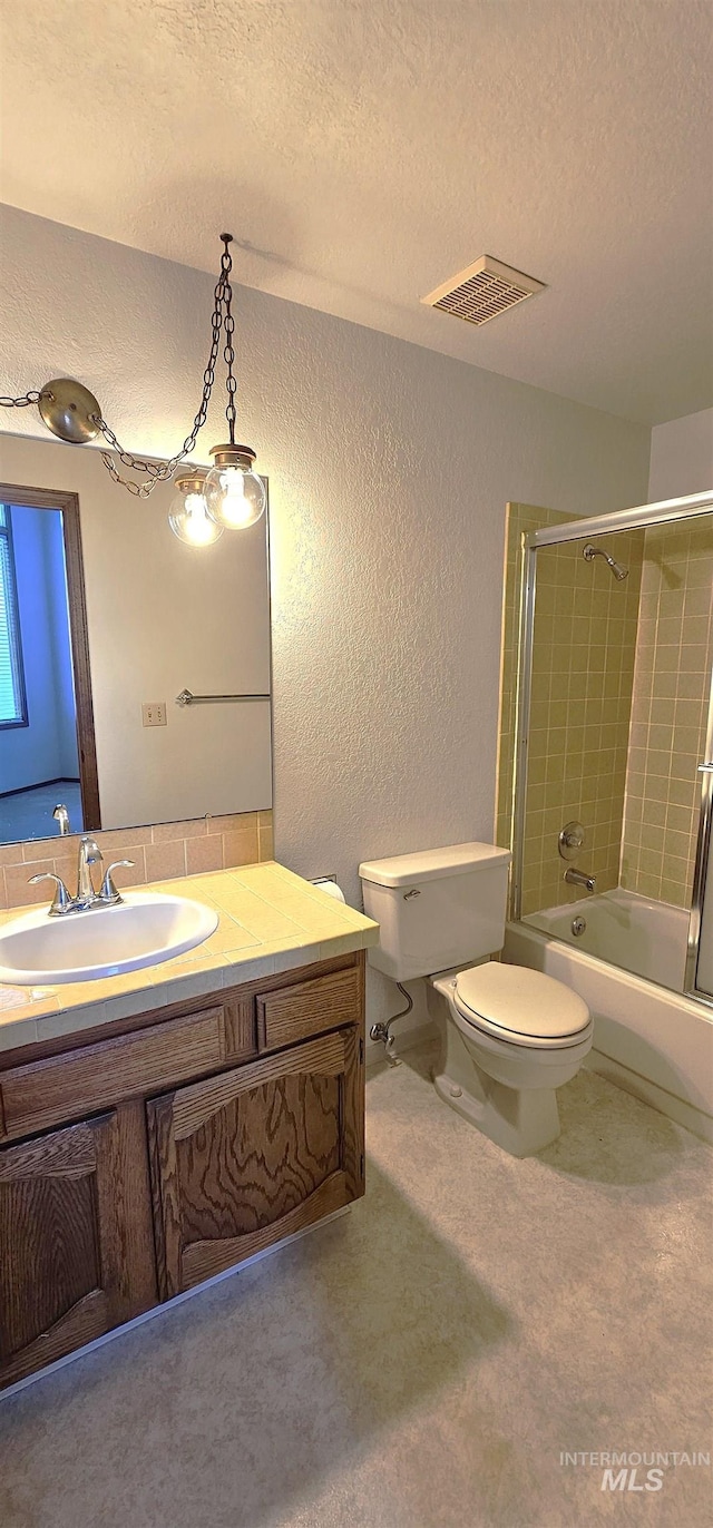 full bathroom featuring vanity, tiled shower / bath, toilet, and a textured ceiling