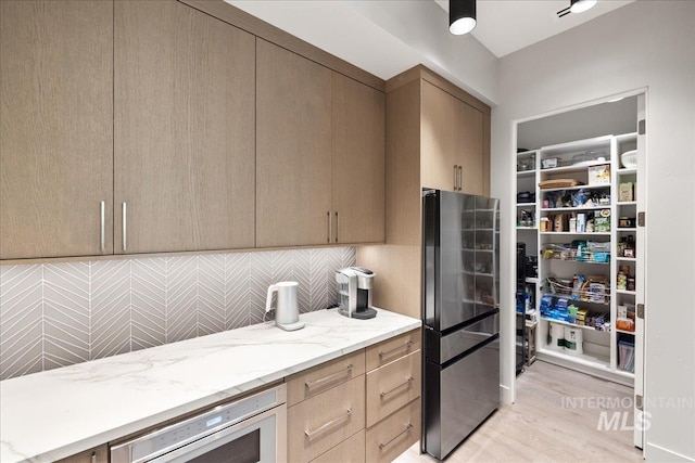 1865 E Lone Shore Ln, Eagle, ID 83616 - kitchen featuring light wood-type flooring, appliances with stainless steel finishes, backsplash, and light stone countertops