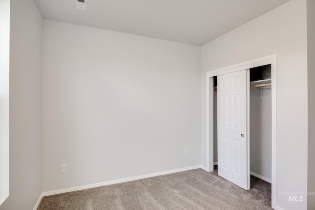 unfurnished bedroom with baseboards, carpet flooring, a closet, and visible vents