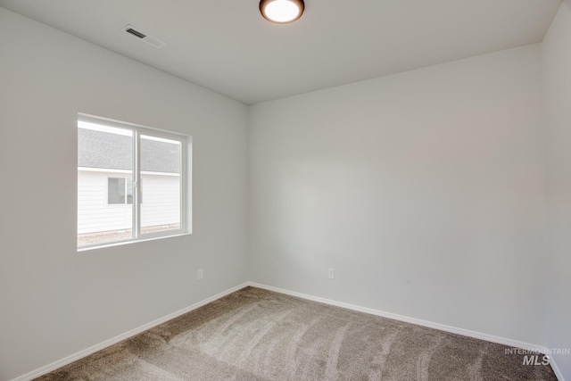 carpeted empty room featuring baseboards and visible vents