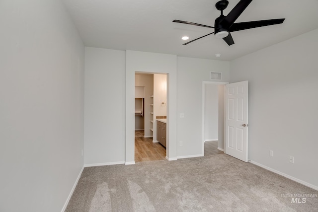unfurnished bedroom with baseboards, light carpet, connected bathroom, and visible vents