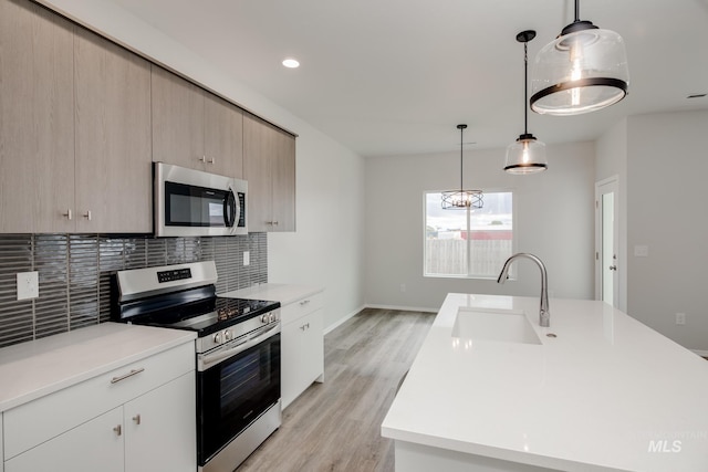 kitchen featuring light countertops, tasteful backsplash, appliances with stainless steel finishes, and a sink
