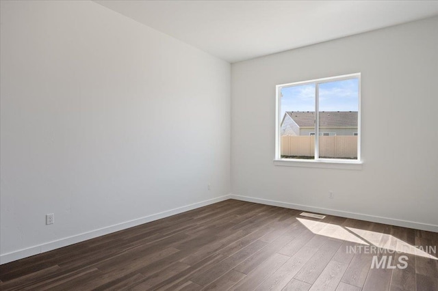 empty room featuring baseboards and dark wood-style flooring