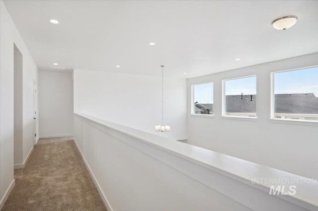 hall with carpet, baseboards, an inviting chandelier, and recessed lighting