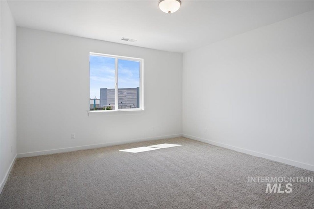 carpeted spare room featuring visible vents and baseboards