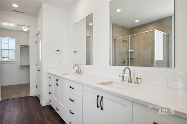 full bathroom featuring a shower stall, visible vents, wood finished floors, and a sink