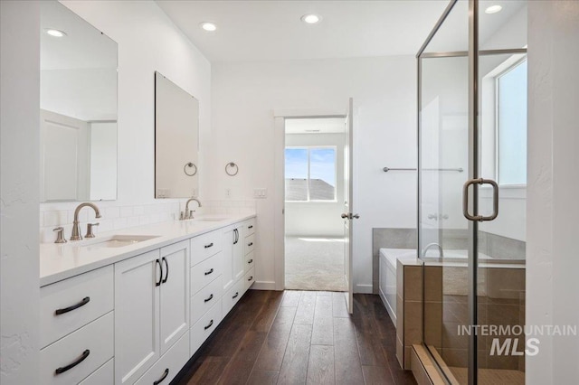 bathroom featuring a stall shower, a sink, double vanity, and hardwood / wood-style floors
