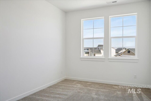 empty room featuring baseboards, carpet flooring, and visible vents